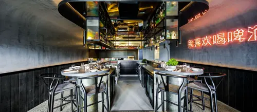 Guests seated along the dark counter at Eddy + Wolff, with the open kitchen and bar behind them