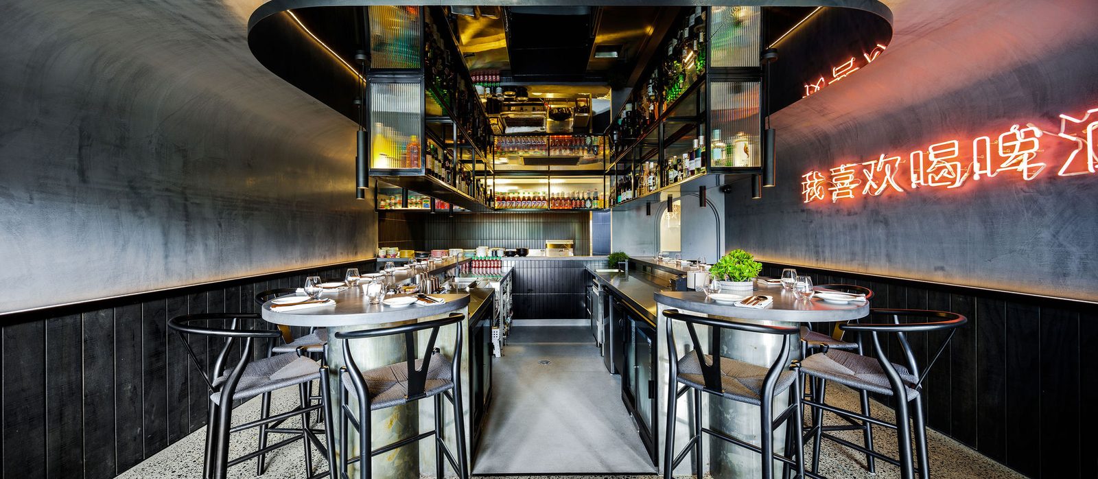 Guests seated along the dark counter at Eddy + Wolff, with the open kitchen and bar behind them