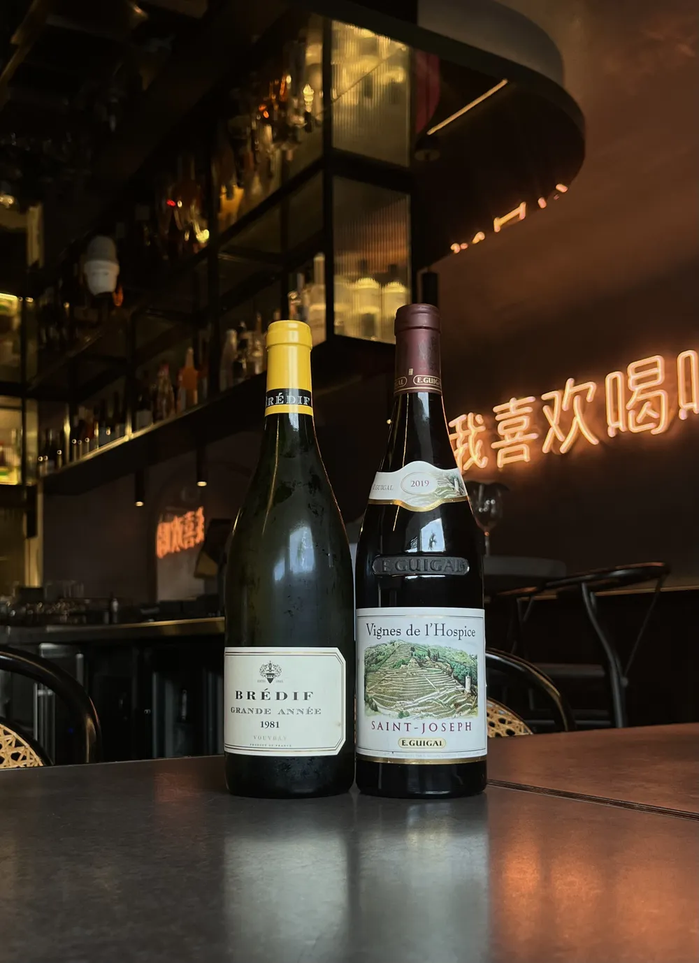 Two bottles from the Eddy + Wolff secret cellar, with the bar behind them